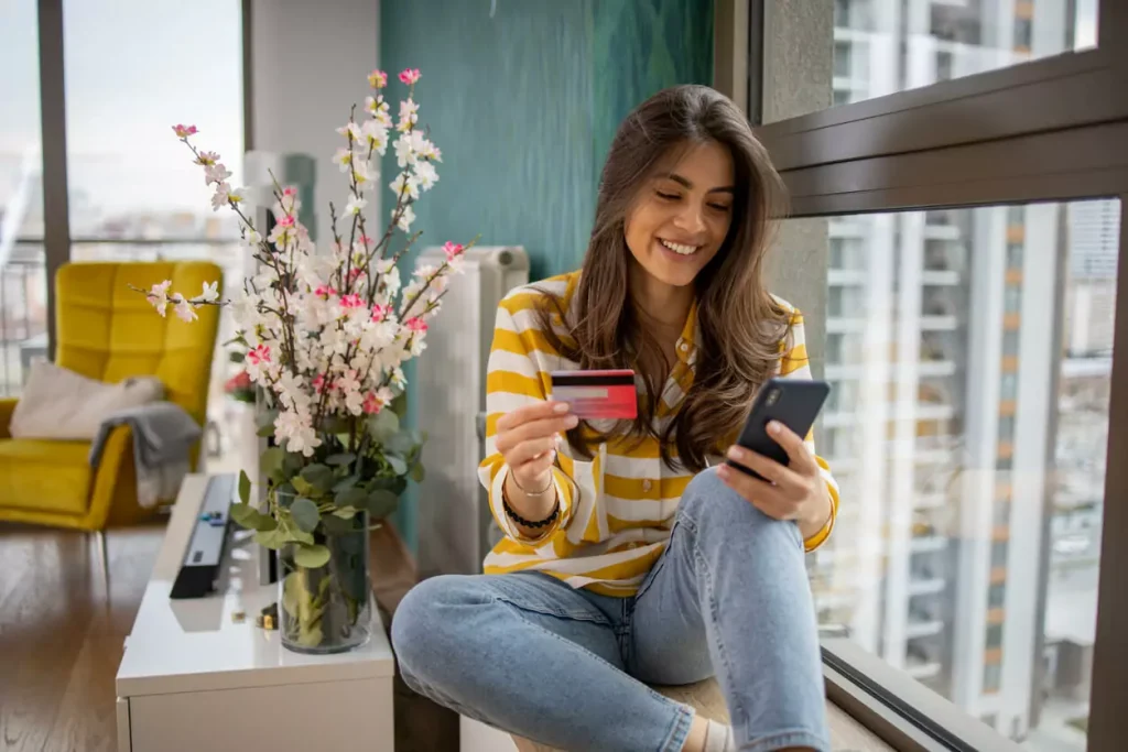 Woman shopping in an online shop on her phone with a credit card in hand